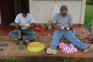 Omar (left) attaching the electrical cable to the submersible pump.  Chente is putting together the control assembly 